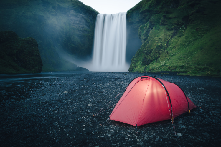 Ein rotes Zelt vor einem Wasserfall in Island