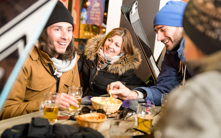 Feiernde Menschen sitzen beim Après-Ski