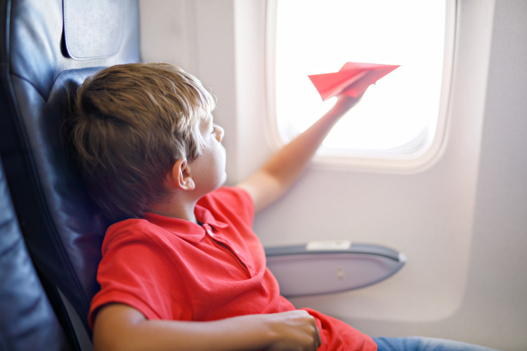 Kind mit Papierflugzeug im Flugzeug